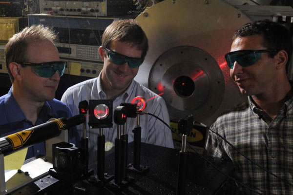 Professor working with laser equipment with two students