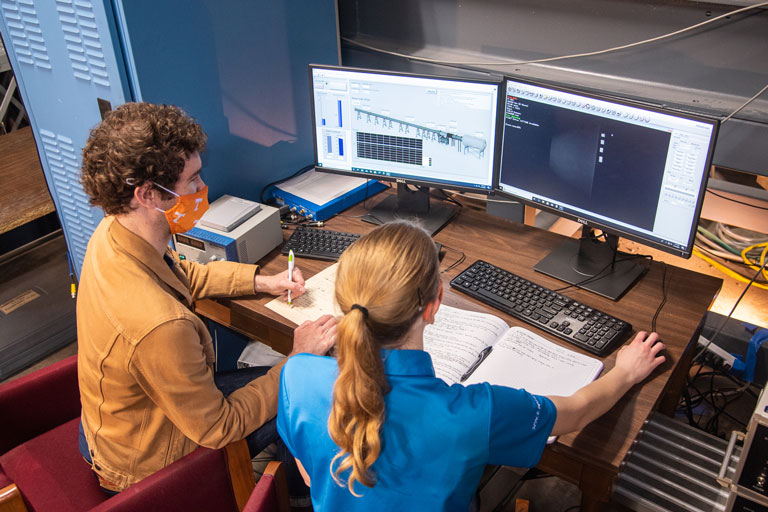 student and professor working on research on a computer
